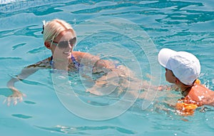 Beautiful woman and little boy bathes in pool