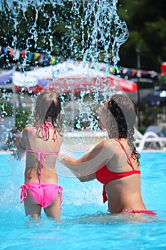 Beautiful woman and little girl bathes in pool photo