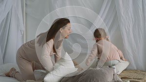 Beautiful woman and little girl play with pillows