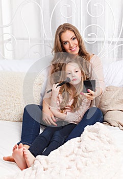 Beautiful woman and little girl putting makeup on photo