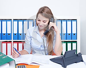 Beautiful woman with long blond hair at office talking at phone