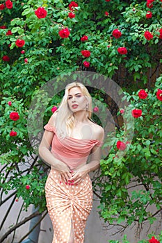 Beautiful woman with long blonde hair and red lips wearing pink clothes