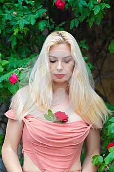 Beautiful woman with long blonde hair and red lips wearing pink clothes