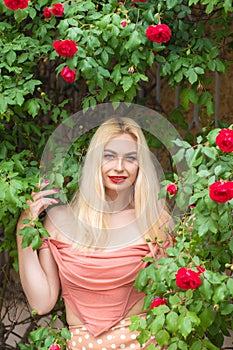 Beautiful woman with long blonde hair and red lips wearing pink clothes