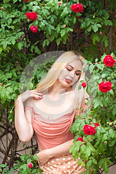 Beautiful woman with long blonde hair and red lips wearing pink clothes