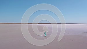 Beautiful woman in long blue dress walking towards camera alone in salt dessert.