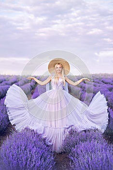 Beautiful woman in a long dress on a background of lavender . A girl in the form of a fairy and a nymph of flowers