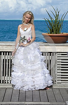 Beautiful woman in a long dress of the bride on the wooden bridge on the tropical island