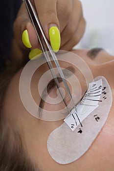 Beautiful Woman with long eyelashes in a beauty salon. Eyelash extension procedure. Lashes close up.