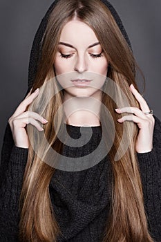 Beautiful woman with long, gorgeous dark blond hair. She is dressed in warm gray knit dress with a hood.