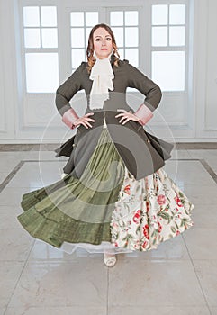 Beautiful woman in long green medieval dress and frock-coat dancing