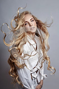 Beautiful woman long hair coloring in ultra blond, natural make-up. Stylish hairstyle curls done in a beauty salon. Fashion blonde