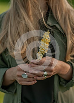 Beautiful woman with long hair holding flower. Hands with rings stylish boho accessories. No focus