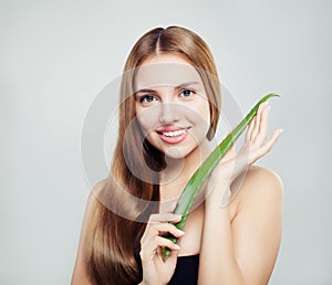 Beautiful woman with long healthy hair holding aloe leaf