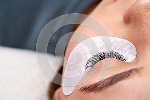 Beautiful Woman with long lashes in a beauty salon. Eyelash extension procedure