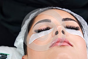 Beautiful Woman with long lashes in a beauty salon. Eyelash extension procedure