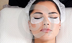 Beautiful Woman with long lashes in a beauty salon. Eyelash extension procedure