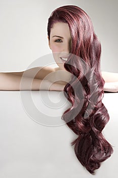 Beautiful woman with long red dyed hair against gray background
