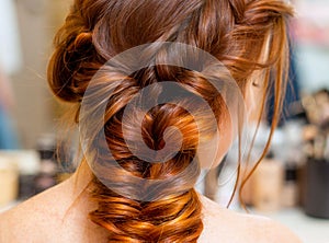 Beautiful woman with long red hair at the beauty salon, hairdresser braided a braid in a beauty salon. Professional hair care and