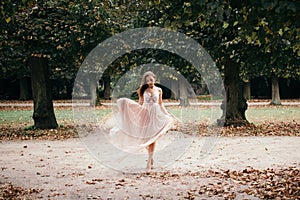 Beautiful woman in long rose evening dress walking path in park.