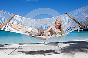 Beautiful woman in a long sundress in a hammock on a sea background