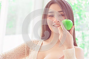 Beautiful woman is looking at apple with happy face for healthy and bea