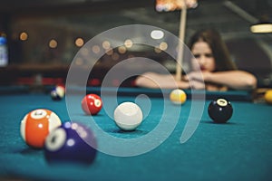 Beautiful woman looking at billiard balls on table