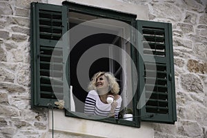 Beautiful woman is looking into the distance with cup of coffee in her hands