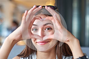 Beautiful woman looking through heart gesture made with hands
