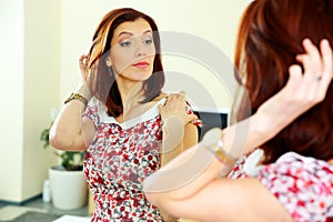 Beautiful woman looking on her reflection in the mirror