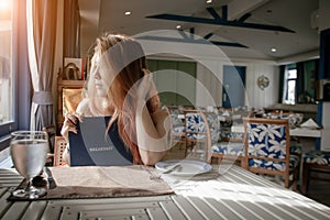 Beautiful woman looking restaurant menu deciding what to order.