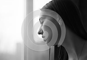 Beautiful woman looking through a window. Selective foc