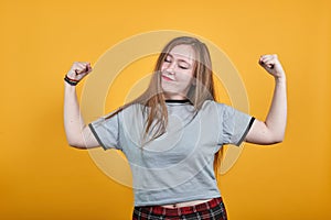 Beautiful woman looks happy and excited doing winner gesture with arms raised