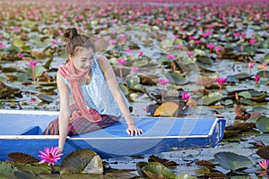 Beautiful woman with lotus flower at the red lotus sea