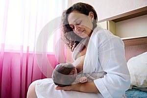 Beautiful woman loving caring mother breastfeeds her baby. Newborn sucking mom& x27;s breast.