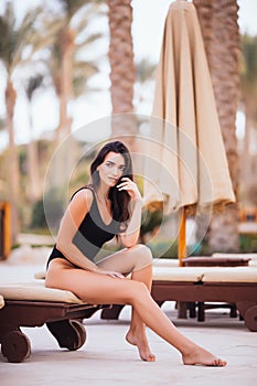 Beautiful woman lying on a deckchair at the beach under palms