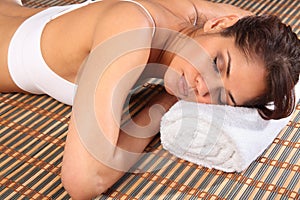 Beautiful woman lying face down in spa on towel