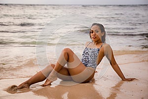 Beautiful woman lying on sandy beach near the ocean. Sexy body. Tanned skin. Asian woman wearing bikini. Summer concept. Vacation