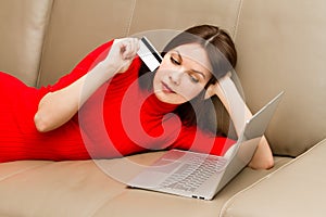 Beautiful woman lying on the sofa with laptop.