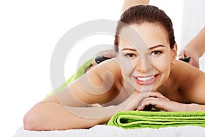 Beautiful woman lying on spa salon having stone massage.