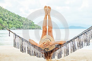 Beautiful woman lying on a tropical beach with legs raised up high in the air