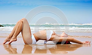 Beautiful woman lying on the wet sand