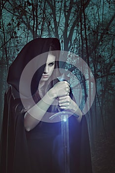 Beautiful woman with magic sword in a dark forest
