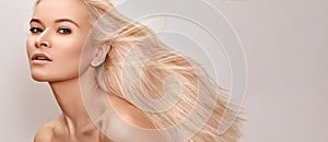 Beautiful woman with magnificent blond hair. Happy model face with windswept flying hair. Shiny long health hairstyle