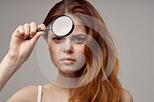 beautiful woman magnifier near the face hygiene close-up