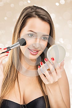 Beautiful woman with make-up mirror and makeup brush