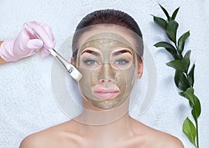 A beautiful woman makes a anti wrinkle mask on her face, she is holding a cotton flower in her hands. Spa treatments and face care