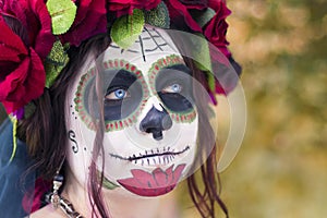 Beautiful woman in makeup traditional Mexican Calavera skull Katrina in the autumn forest, in a wreath of red flowers. Day of the