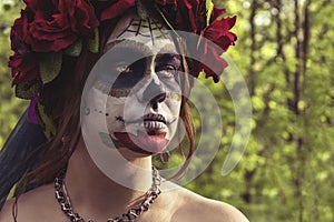 Beautiful woman in makeup traditional Mexican Calavera skull Katrina in the autumn forest, in a wreath of red flowers. Day of the