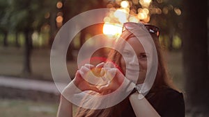 Beautiful Woman making heart shape with hands at sunset